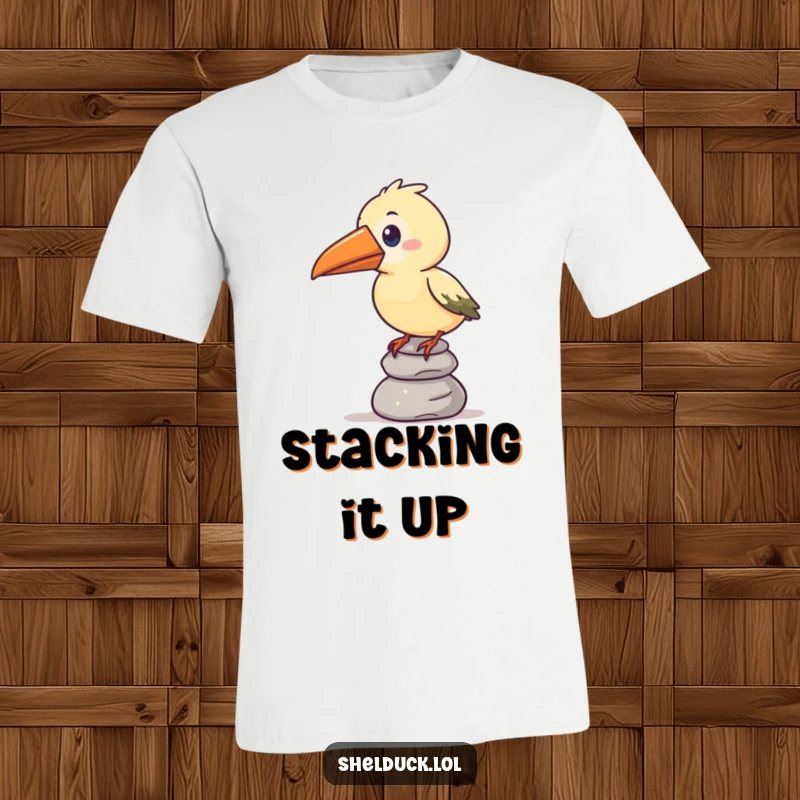 Funny t-shirt depicting a stylized bird with an oversized beak precariously balancing a stack of pebbles, symbolizing effort.